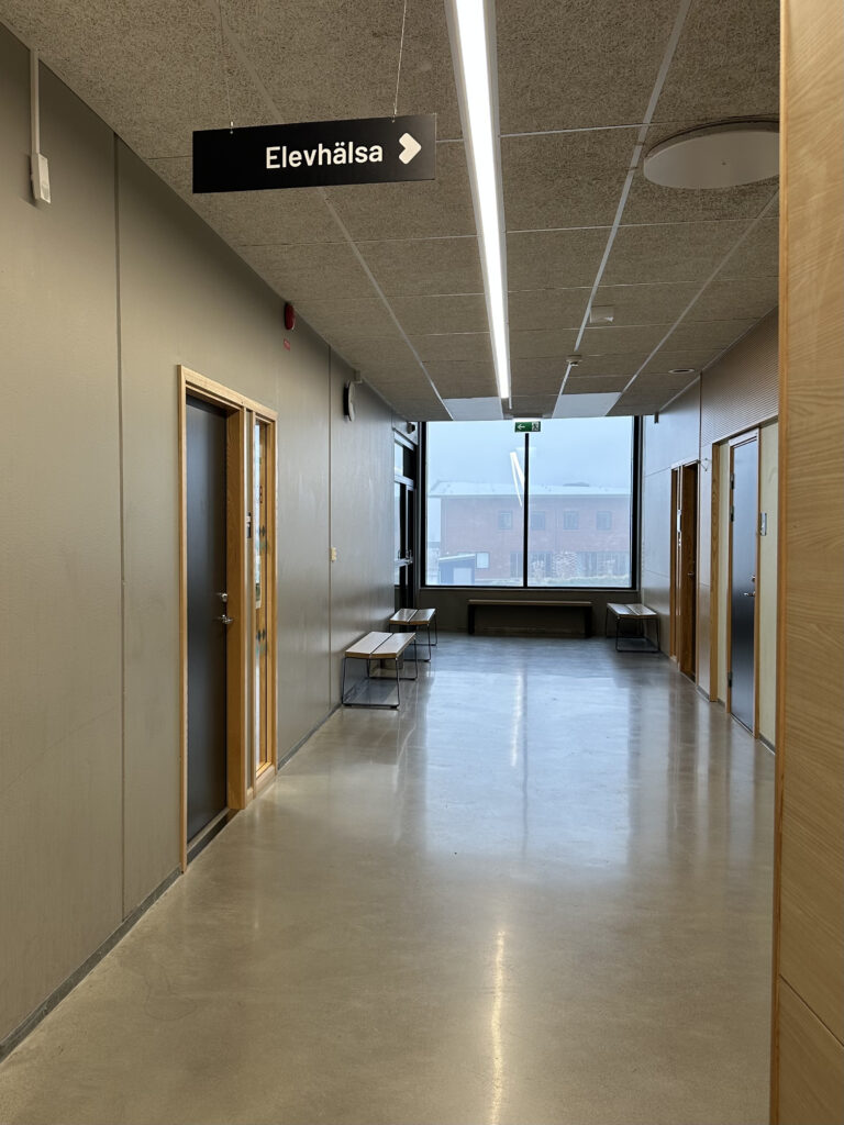 Korridor utanför skolans elevhälsa med dörrar till samtalsrum och en lugn väntplats.